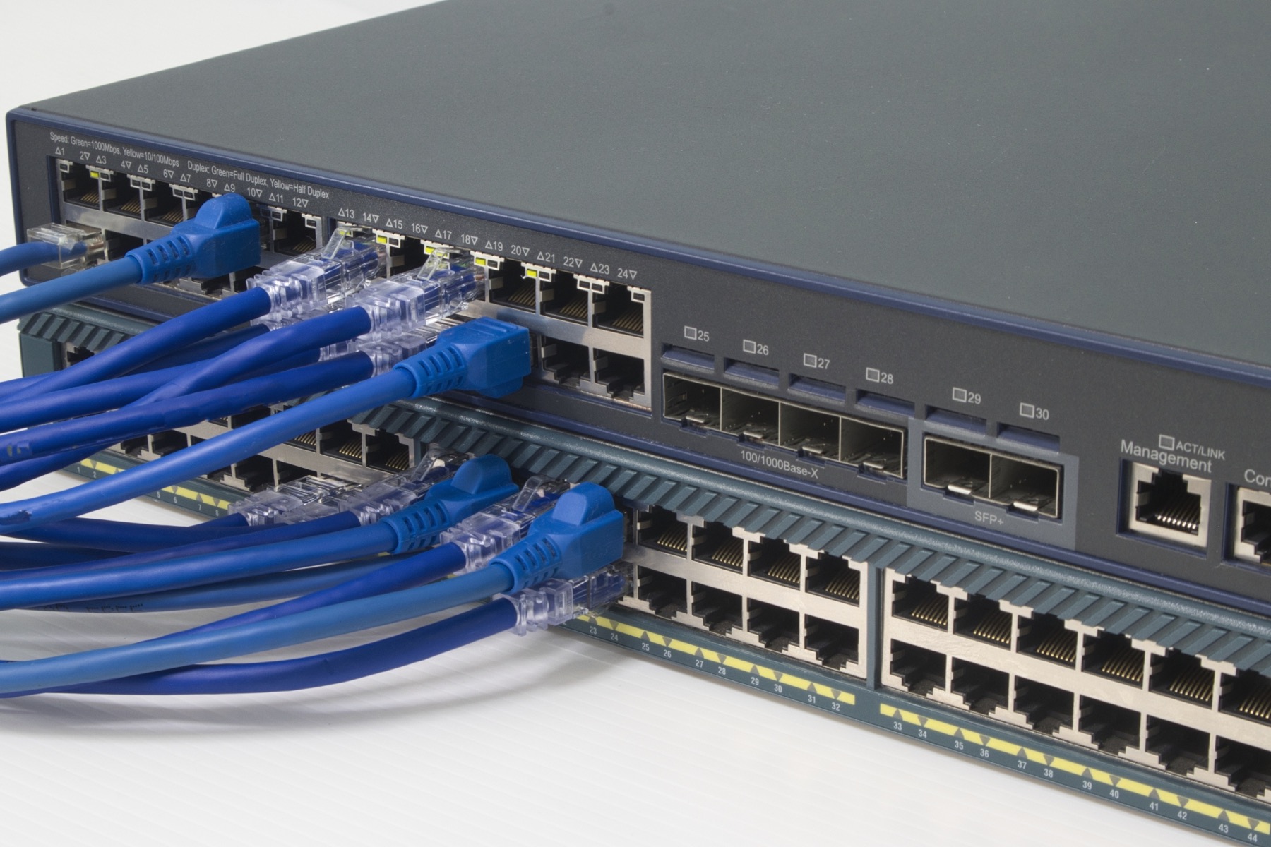 青いLANケーブルが接続された2台のネットワークスイッチ